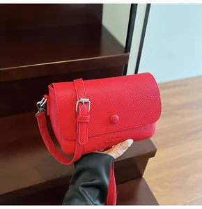 Détail du sac bandoulière en cuir rouge grainé avec logo CLEAR et boucles argent