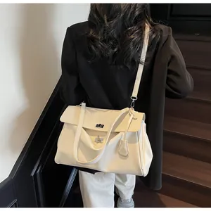 Close-up of a white leather shoulder bag with metal turn-lock and accordion pleats