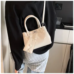 Gros plan du sac en cuir verni crème avec fermoir rotatif argenté et mini pochette