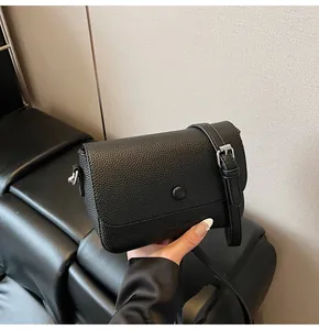 Gros plan détaillé du sac en cuir noir grainé avec boucle de bandoulière réglable