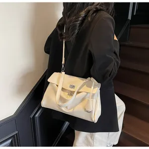 Close-up of a cream underarm bag with silver twist lock and crossbody strap shown on model