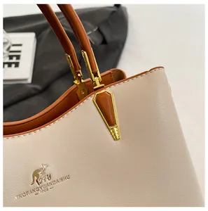 Close-up of golden kangaroo logo and brand text on premium cream and tan leather handbag