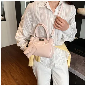 Détail du sac à main en cuir verni rose clair avec fermoir argenté et petit pendentif