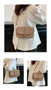Detail showing khaki crossbody bag with grain texture and silver metal buckle accent