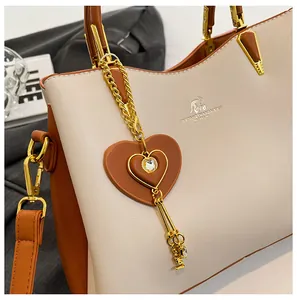 Close-up of golden kangaroo logo and crystal heart charm on cream leather handbag