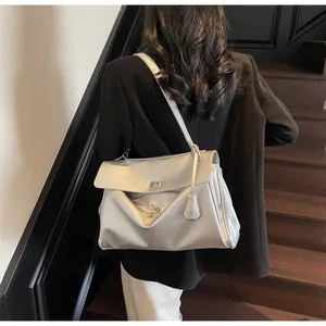 Detail of silver metallic shoulder bag featuring a sleek turn-lock closure and leather tag