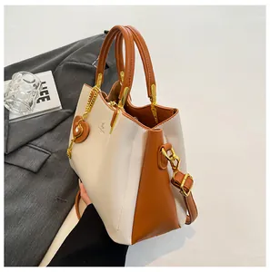Detail of two-tone soft leather handbag with heart charm and gold hardware accents