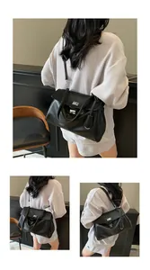 Detail of a black minimalist shoulder bag showing the texture, strap and rotating clasp