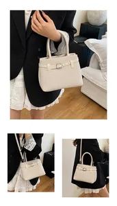 Detail view of beige woven texture handbag with silver metal buckle and adjustable strap