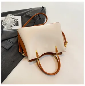 Close-up of cream and brown patchwork leather tote with gold hardware and metal feet