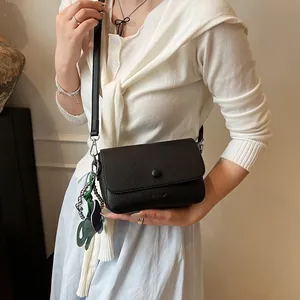 Sac bandoulière en cuir grainé noir avec rabat et breloque éléphant vert