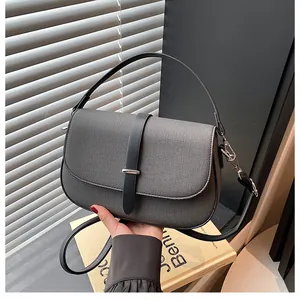 Detail of grey textured saddle bag with silver metal buckle and black leather handle