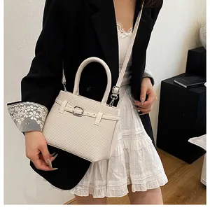 Detail view of cream textured crossbody bag with metal buckle and adjustable strap