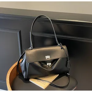 Detail of minimalist black leather underarm bag featuring dual silver metal twist locks