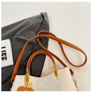 Detail of soft cream PU leather bag with brown handles and golden kangaroo logo