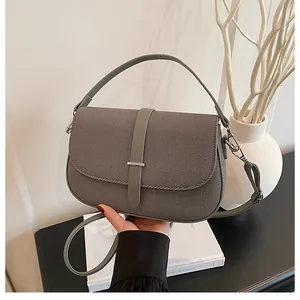 Detail of grey crossbody bag featuring twill texture, silver hardware and top handle strap