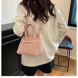 Pink woven texture handbag with silver buckle and crossbody strap detail shown on model
