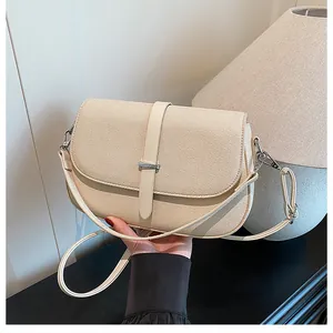 Detail of a cream woven crossbody bag with leather strap and silver metal hardware hook