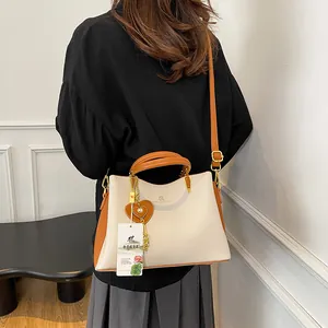 Elegant beige and orange leather handbag with kangaroo logo and adjustable shoulder strap