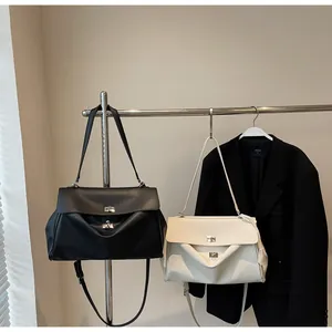 Close-up of black and beige PU leather handbags with silver metal twist lock detail