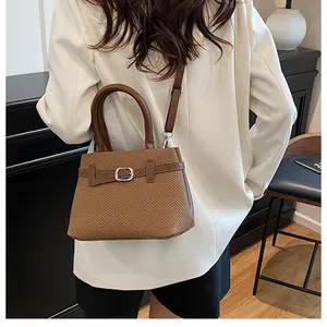 Brown woven handbag and shoulder strap detail on a model wearing a white blazer