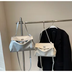Detail of silver-grey and beige leather shoulder bags with metal twist locks and fold accents
