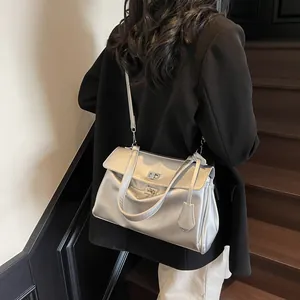 Silver metallic minimalist shoulder bag with turn-lock clasp shown on a model