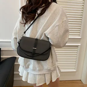 Minimalist black crossbody bag with woven texture and silver buckle shown on model