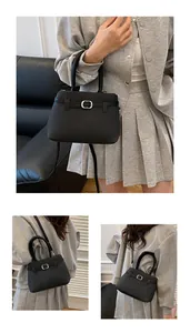 Detail of black woven texture leather handbag with silver oval metal buckle and strap