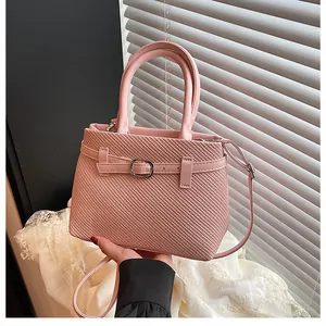 Detail of pink woven texture handbag with metal buckle and adjustable shoulder strap