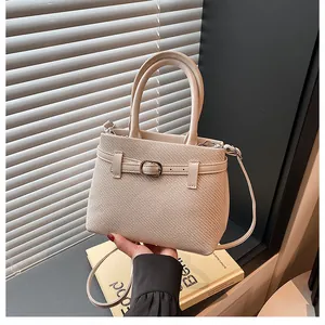 Detail of beige woven texture handbag with dual handles and metal buckle strap