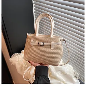 Detail showing the woven texture of the beige handbag with elegant buckle and strap
