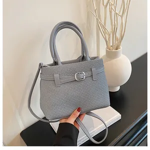 Detail of grey woven texture handbag with decorative strap buckle and adjustable shoulder strap