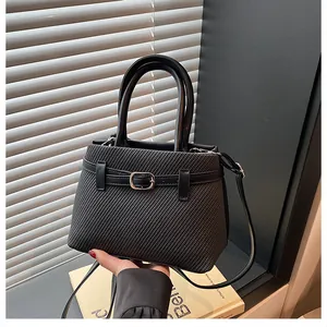 Detail of black textured fabric handbag with leather trim and silver metal buckle