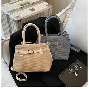Detailed view of woven texture tote bags in beige and grey with metallic buckle details