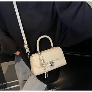 Close-up of cream leather crossbody bag with silver twist lock and woven rope charm