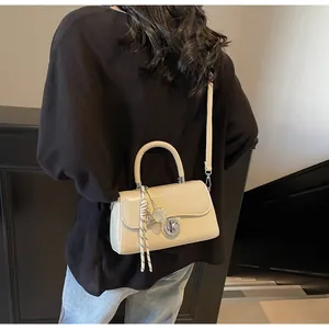 Detail view of cream small square crossbody bag with silver twist lock and pendant