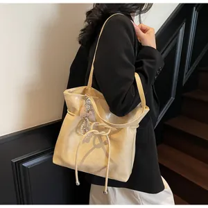 Détail d'un sac cabas beige plissé brillant avec breloque perle sur un mannequin chic