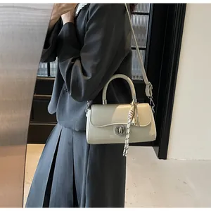 Detail of cream square handbag with silver twist lock and woven rope charm accessory