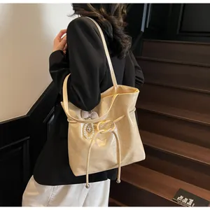 Mannequin portant un sac cabas crème brillant avec perles et ruban à carreaux