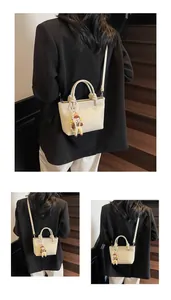 Detail of cream white bucket bag with pebble texture and cute cartoon charm