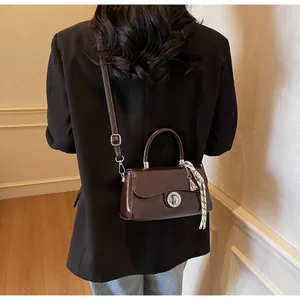 Brown retro leather handbag with silver clasp and scarf detail worn over a black blazer