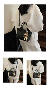 Detail view of black lychee grain leather bucket bag with a cute cartoon doll charm