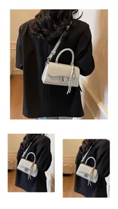 Detail of light grey square crossbody bag with metallic rotary lock and woven strap