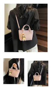 Detail of pink lychee leather mini bucket bag with cute doll pendant and adjustable strap