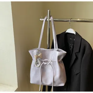Détail du sac cabas lilas en cuir texturé avec nœud décoratif et pendentif élégant