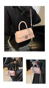 Detail view of pink square crossbody bag showing silver twist lock and woven charm