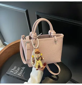 Detail of pink lychee leather handbag featuring decorative pearl charm and silver hardware