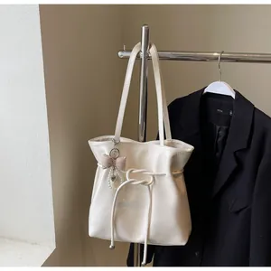 Détail du sac cabas en cuir texturé crème avec breloque élégante et ruban chic