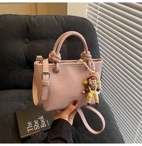 Detailed macro view of the pink lychee leather texture and the cute doll charm on the bag